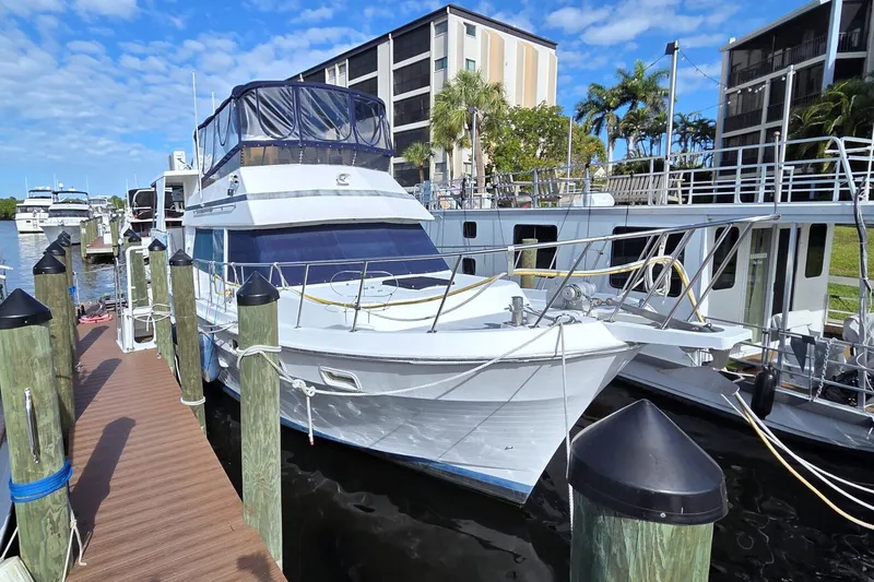 Slide: The Image of 1984 Present Yachts 42 Sundeck docked at marina, surrounded by palm trees and buildings. - 82