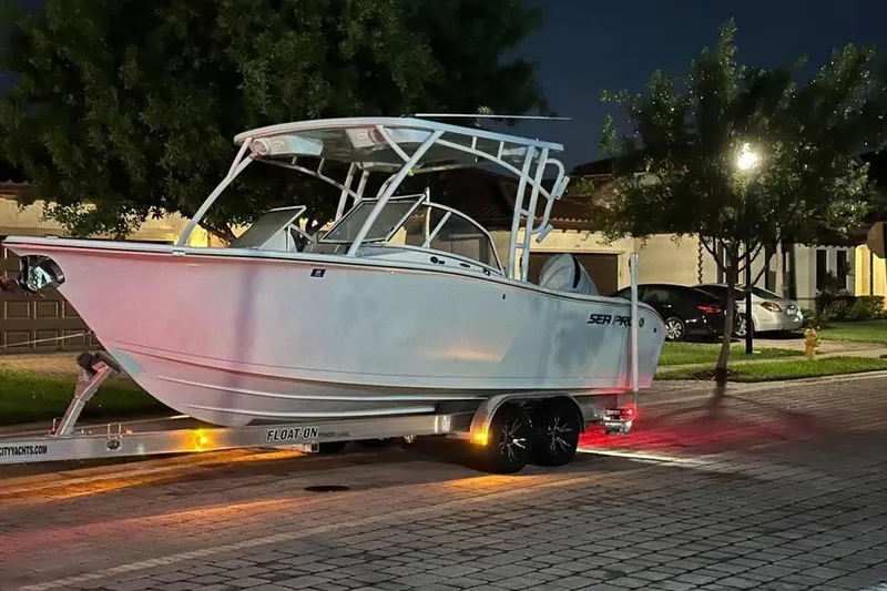 The Image of 2025 Sea Pro 240 Dual Console boat on trailer, parked outdoors under clear blue sky. - 0
