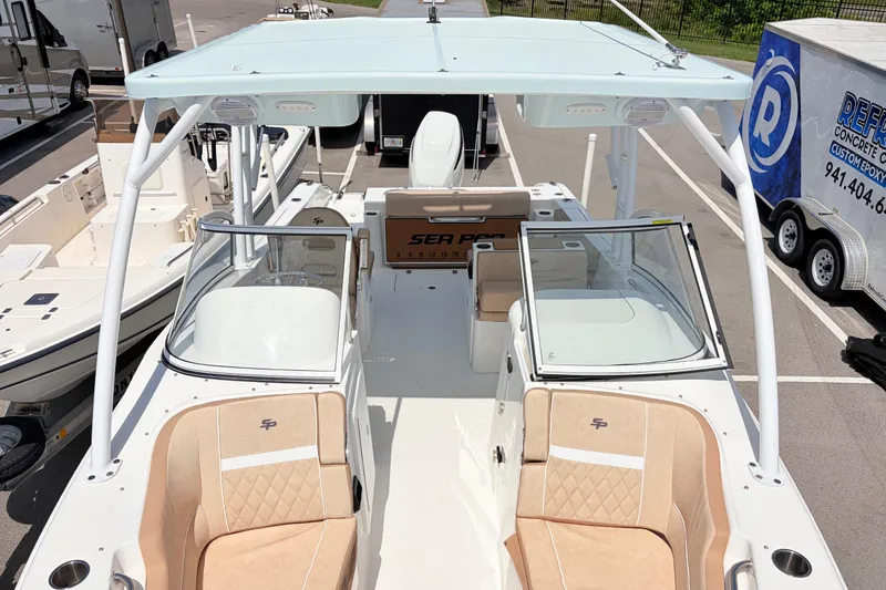 Slide: The Image of 2025 Sea Pro 240 Dual Console boat with tan seating and white canopy in a marina. - 17