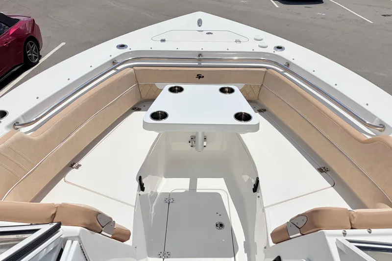 Slide: The Image of 2025 Sea Pro 240 Dual Console boat interior with seating and table, parked in a lot. - 18