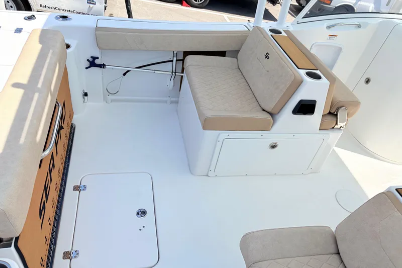 Slide: The Image of 2025 Sea Pro 240 Dual Console boat interior with beige seating and storage compartments. - 35