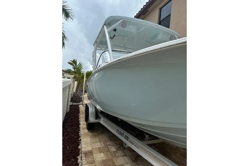 Slide: The Image of 2025 Sea Pro 240 Dual Console boat on trailer, parked outdoors under clear sky. - 5