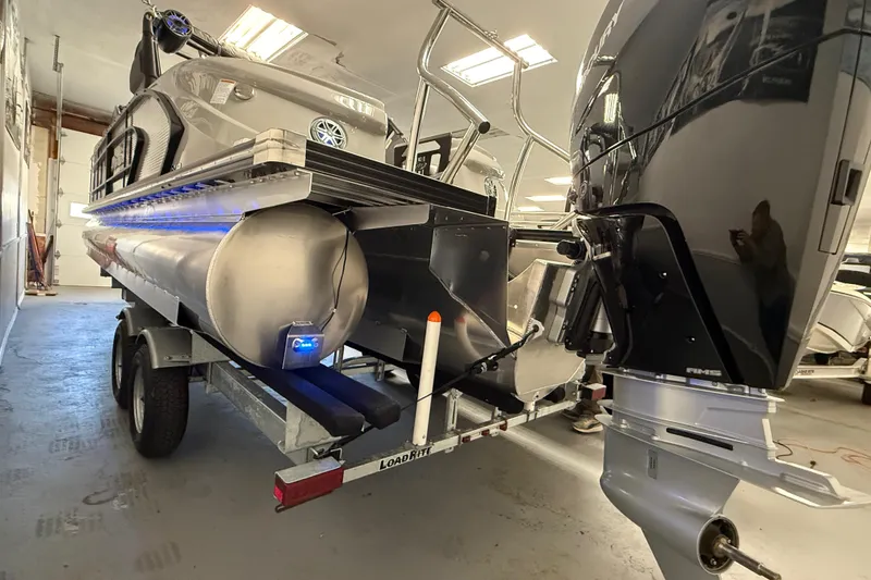 Slide: The Image of 2026 Manitou 25 LX RFW pontoon boat on trailer in a garage setting. - 10