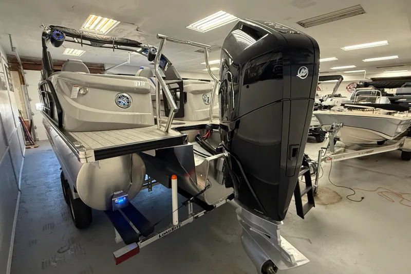 Slide: The Image of 2026 Manitou 25 LX RFW pontoon boat with powerful outboard motor in a showroom. - 11