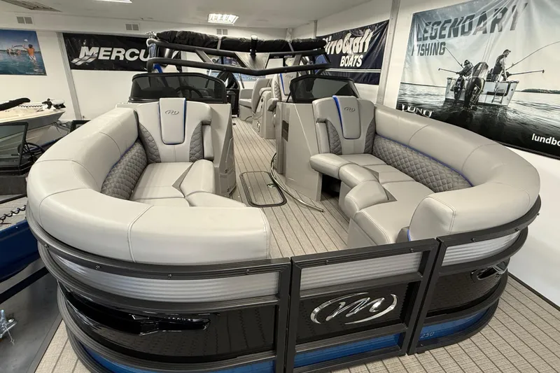Slide: The Image of 2026 Manitou 25 LX RFW pontoon boat with luxurious seating in showroom. - 16