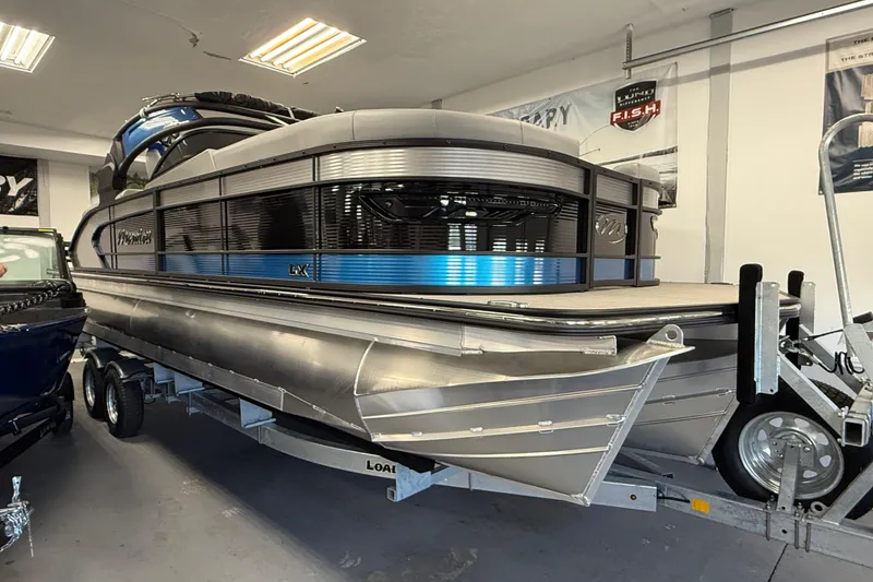 Slide: The Image of 2026 Manitou 25 LX RFW pontoon boat on trailer in showroom. - 17