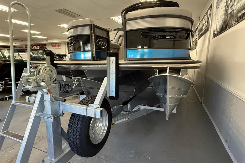 Slide: The Image of 2026 Manitou 25 LX RFW pontoon boat on trailer in showroom. - 3