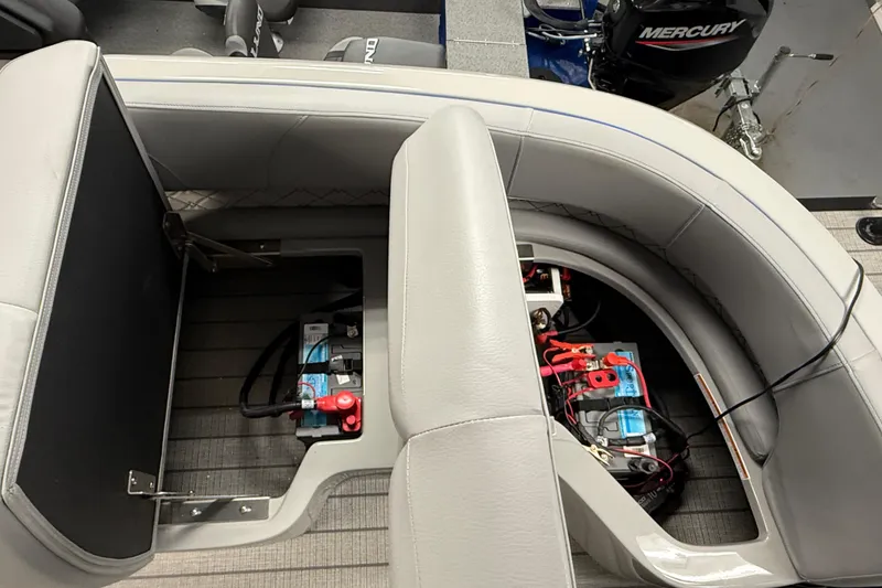 Slide: The Image of Interior view of 2026 Manitou 25 LX RFW boat showing battery compartment under seating. - 5