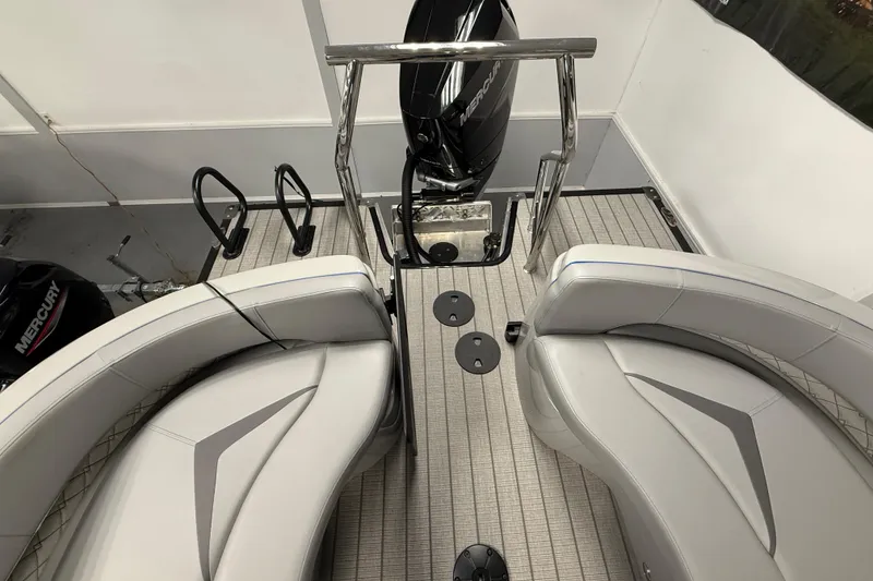Slide: The Image of 2026 Manitou 25 LX RFW boat interior with sleek seating and Mercury engine. - 6
