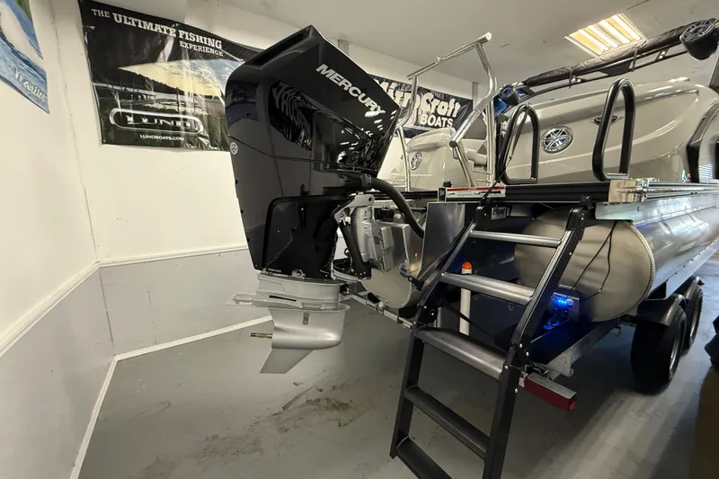 Slide: The Image of 2026 Manitou 25 LX RFW pontoon boat with Mercury outboard motor in showroom. - 9
