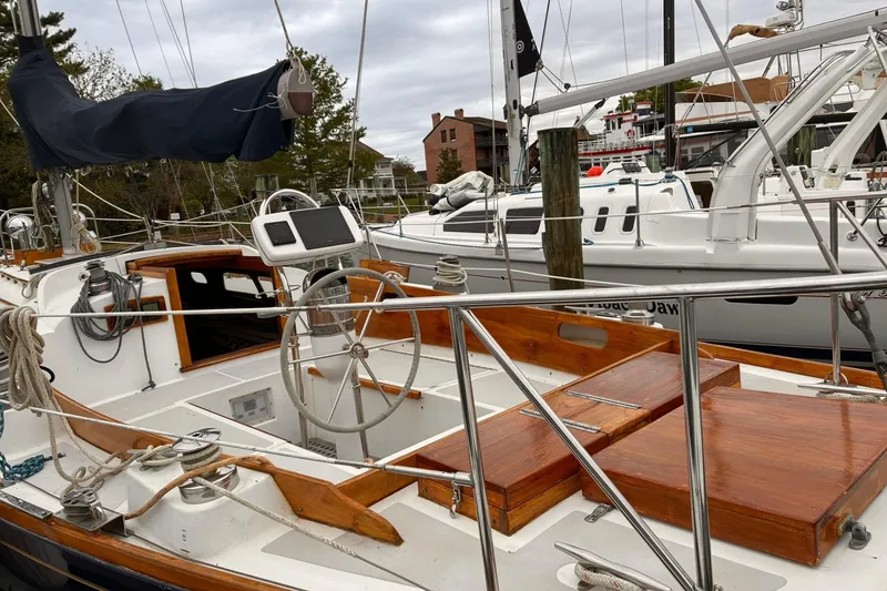 Slide: The Image of 1980 Hinckley Bermuda 40 MKIII sailboat with wooden deck and steering wheel at marina. - 2