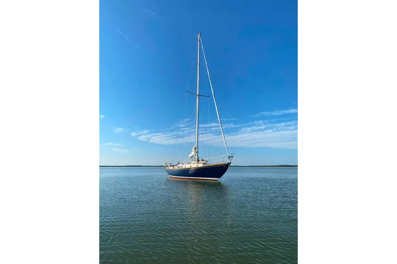Slide: The Image of 1980 Hinckley Bermuda 40 MKIII sailboat on calm water under clear blue sky. - 34