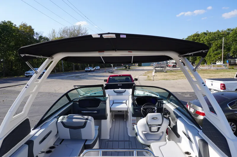 Slide: The Image of 2026 Chaparral 247 SSX boat interior with seating, steering wheel, and canopy, parked outdoors. - 11