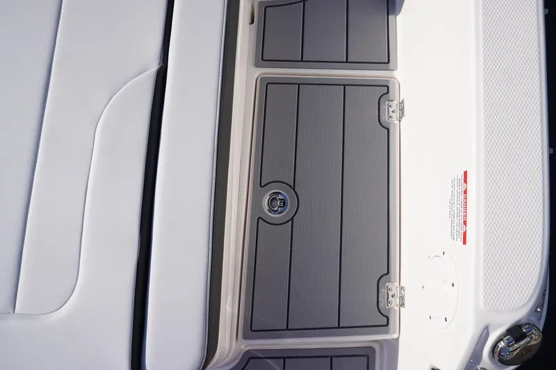 Slide: The Image of 2026 Chaparral 247 SSX boat deck with sleek storage compartment and safety warning label. - 12