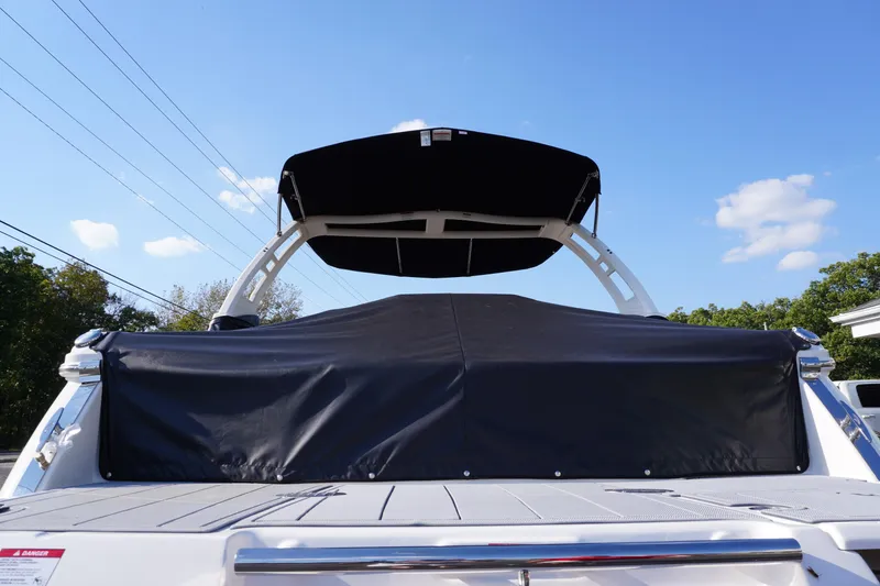 Slide: The Image of 2026 Chaparral 247 SSX boat with black cover and canopy under blue sky. - 38