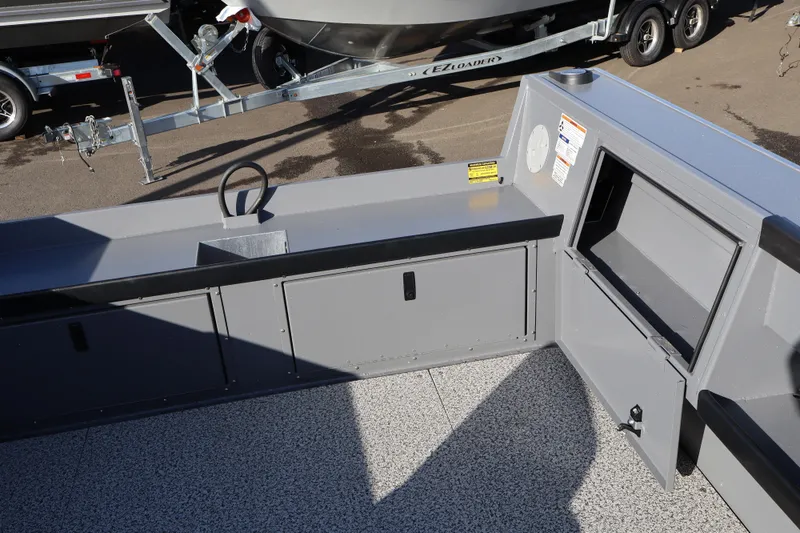 Slide: The Image of 2026 Alumaweld Columbia 23 boat interior with storage compartments and trailer in background. - 19