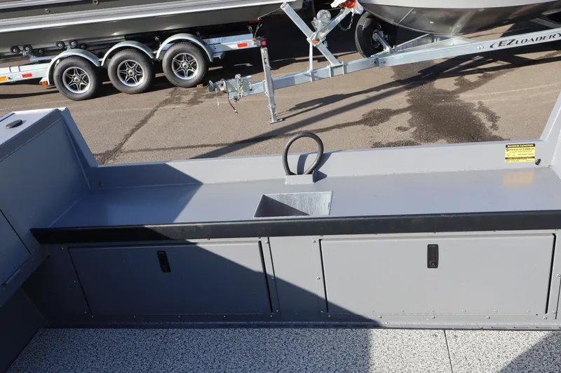 Slide: The Image of 2026 Alumaweld Columbia 23 boat interior with storage compartments and trailer in background. - 20