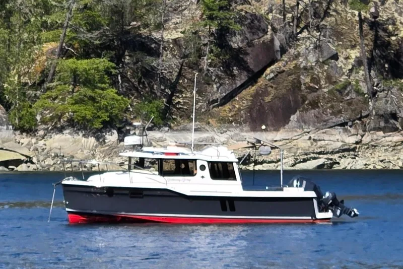 The Image of 2023 Ranger Tugs R-25 boat on calm water near rocky shoreline. - 0