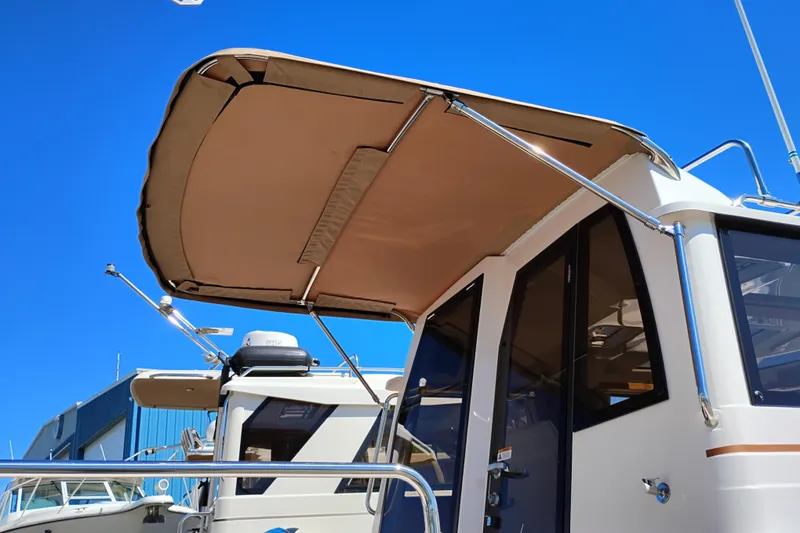 Slide: The Image of 2023 Ranger Tugs R-25 boat with canopy under clear blue sky. - 11