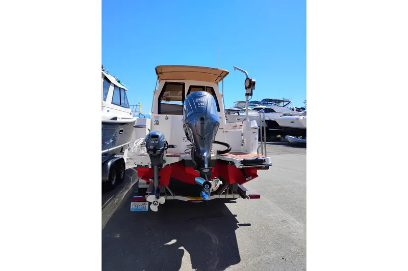 Slide: The Image of 2023 Ranger Tugs R-25 boat with dual outboard motors, docked in a marina. - 12
