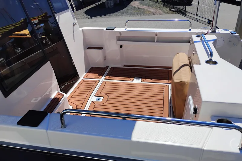 Slide: The Image of 2023 Ranger Tugs R-25 boat deck with teak flooring and stainless steel railings. - 23