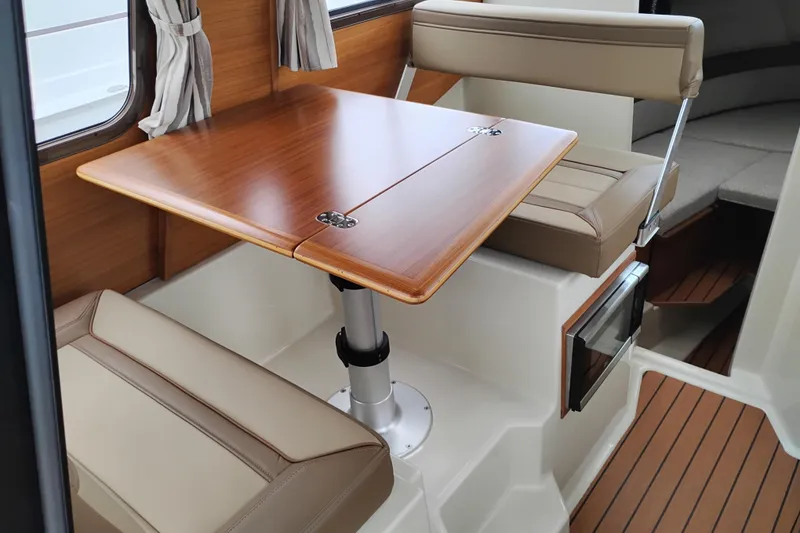 Slide: The Image of Interior of 2023 Ranger Tugs R-25 with wooden table and beige seating. - 35