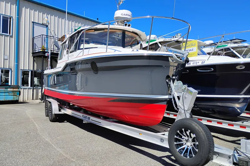 Slide: The Image of 2023 Ranger Tugs R-25 boat on trailer, displayed outdoors near a building. - 4