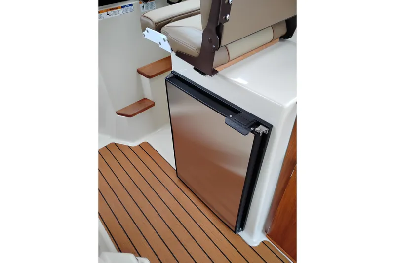 Slide: The Image of 2023 Ranger Tugs R-25 interior with compact stainless steel fridge and wooden steps. - 43
