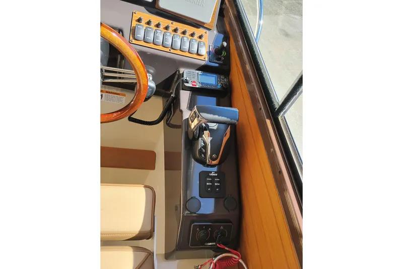 Slide: The Image of 2023 Ranger Tugs R-25 helm with controls, steering wheel, and navigation equipment. - 48