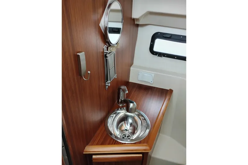 Slide: The Image of 2023 Ranger Tugs R-25 interior with wooden finish, stainless steel sink, and mirror. - 54