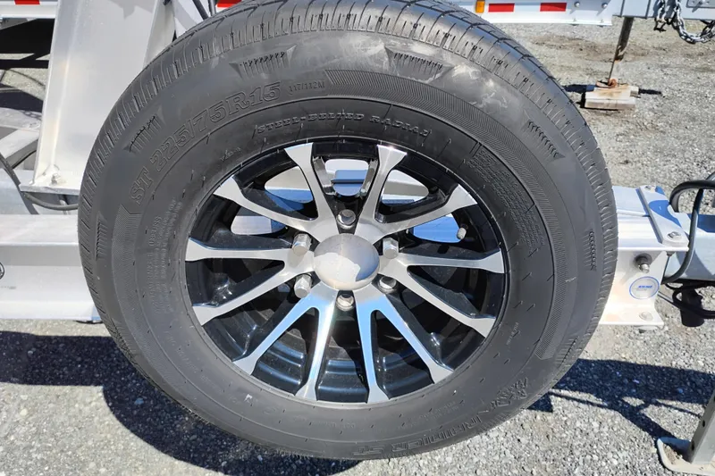 Slide: The Image of Trailer wheel with black alloy rim, tire size ST225/75R15, on gravel surface. - 7