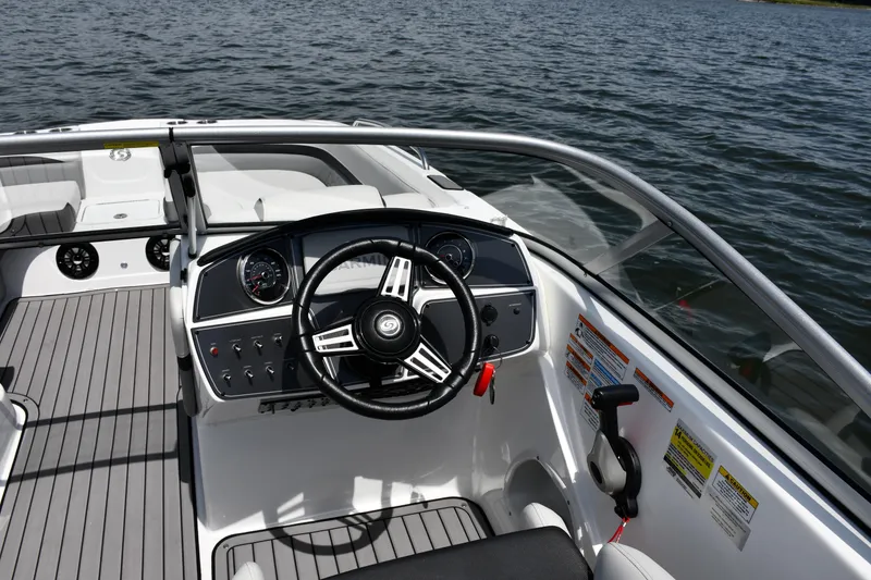 Slide: The Image of 2023 Hurricane SunDeck 217 OB boat cockpit with steering wheel and controls on water. - 10