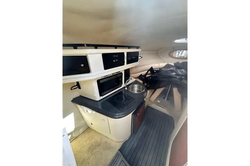 Slide: The Image of Interior of a 2006 Monterey 270 Cruiser boat, featuring a compact kitchenette and seating area. - 10
