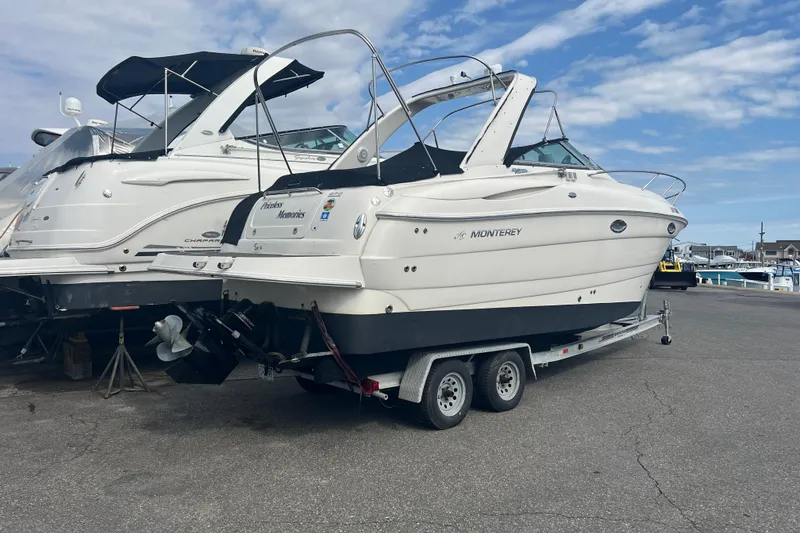 Slide: The Image of 2006 Monterey 270 Cruiser boat on trailer at marina, under a partly cloudy sky. - 21
