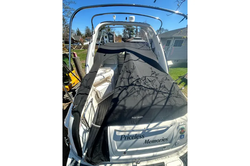 Slide: The Image of 2006 Monterey 270 Cruiser boat with black cover, docked in a residential area. - 23