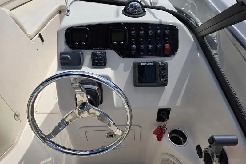Slide: The Image of 2015 Grady-White Freedom 205 boat dashboard with steering wheel and navigation controls. - 12