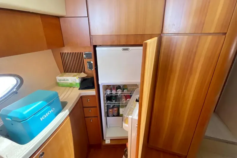 Slide: The Image of 2004 Azimut 46 yacht kitchen with open fridge, wooden cabinets, and countertop cooler. - 17
