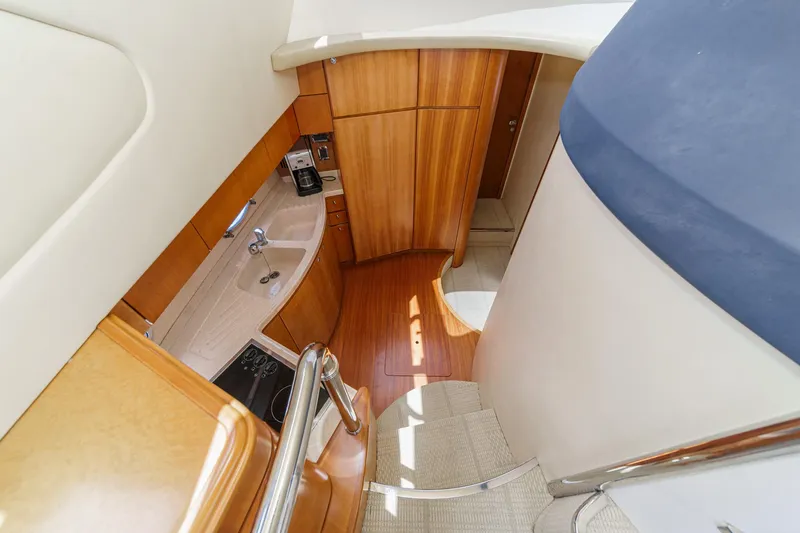 Slide: The Image of Interior of 2004 Azimut 46 yacht, featuring a compact kitchen with wooden cabinetry. - 52