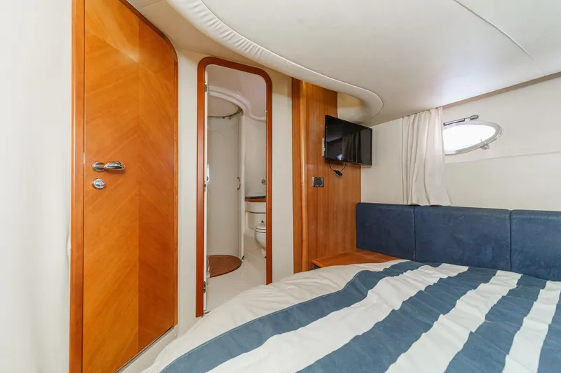 Slide: The Image of Luxurious 2004 Azimut 46 yacht cabin with ensuite bathroom, TV, and stylish wood accents. - 61