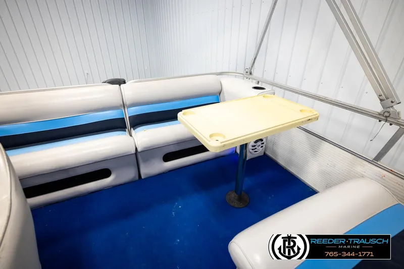 Slide: The Image of Interior of a 1994 Hydra 192-23 boat with blue and white seating and a small table. - 23