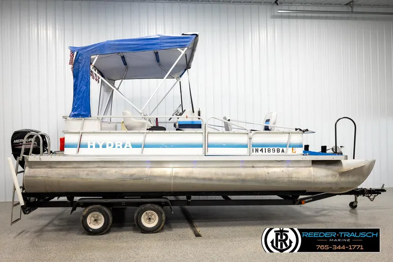 Slide: The Image of 1994 Hydra 192-23 pontoon boat with blue canopy on trailer in indoor setting. - 5