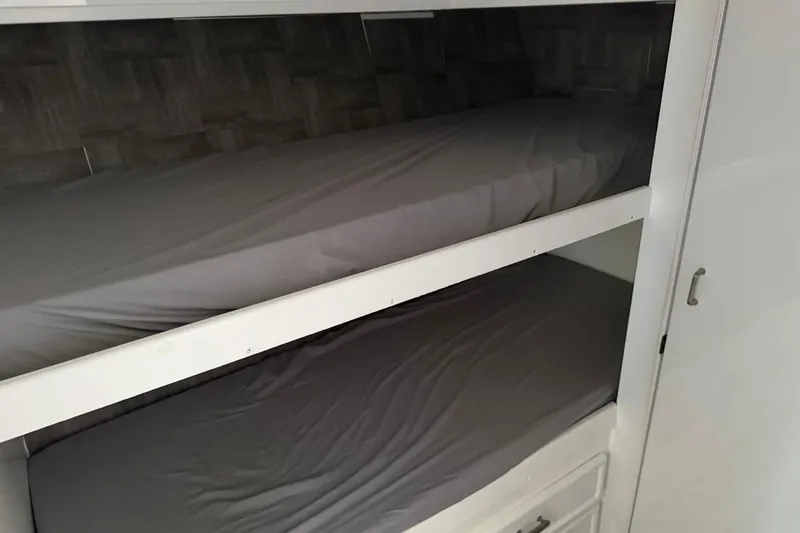 Slide: The Image of Bunk beds inside 1984 Ocean Yachts 55 Super Sport, featuring simple gray bedding. - 29