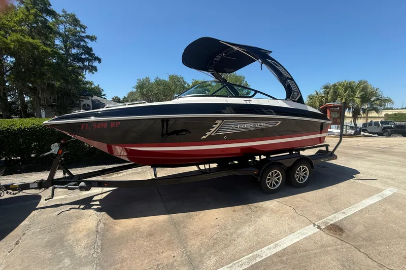 Slide: The Image of 2017 Regal 24 FasDeck boat on trailer, black and red design, parked outdoors. - 10