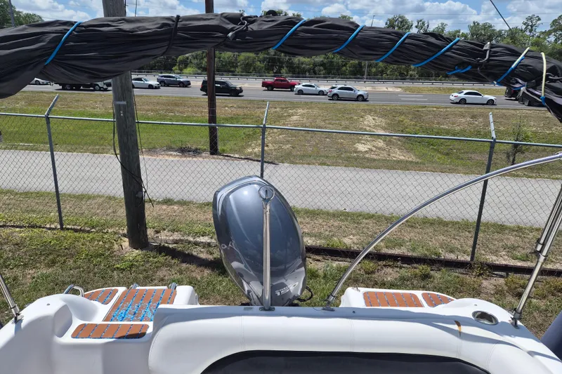 Slide: The Image of 2013 Hurricane FunDeck 226 boat with covered canopy and outboard motor, parked near a road. - 6