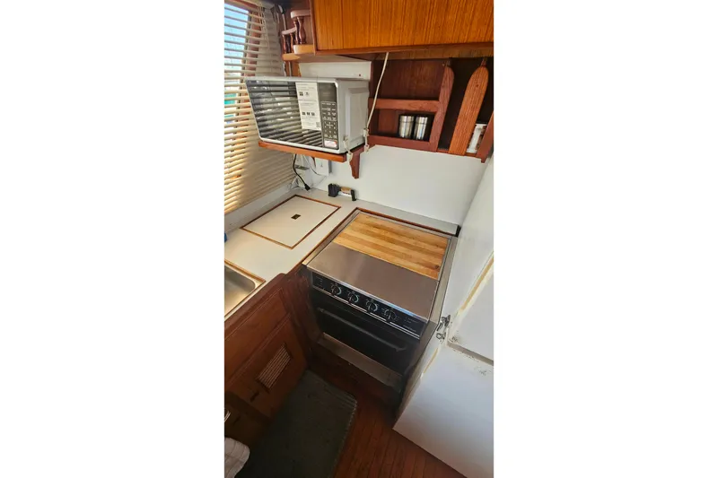 Slide: The Image of Compact kitchen in 1981 Sea Ranger 47 Pilothouse with stove, microwave, and wooden cabinetry. - 11