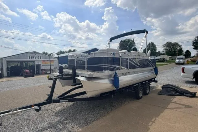 Slide: The Image of 2019 Quest Adventure 818 pontoon boat on trailer at service center under cloudy sky. - 11