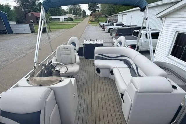 Slide: The Image of 2019 Quest Adventure 818 pontoon boat with spacious seating and canopy, parked near buildings. - 4