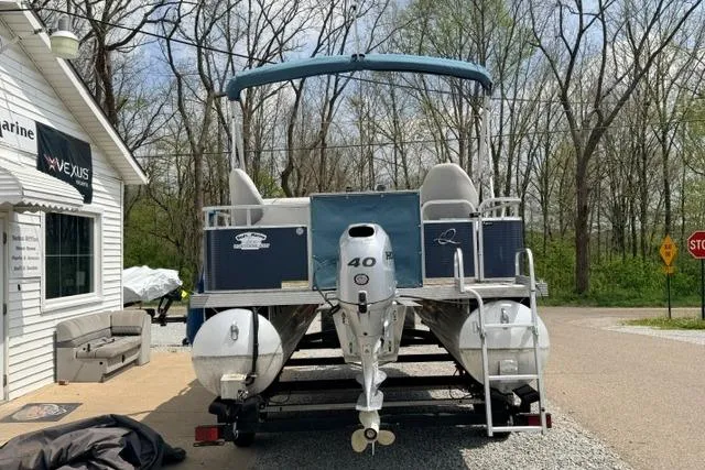 Slide: The Image of 2019 Quest Adventure 818 pontoon boat with canopy, parked near a marine shop. - 9