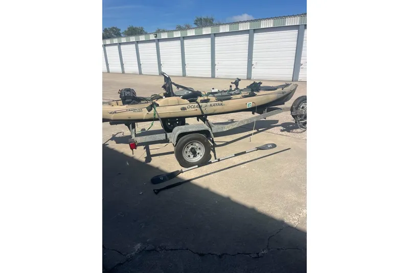Slide: The Image of 2016 East Cape Fury kayak on trailer with paddles, parked near storage units. - 37