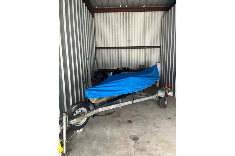 Slide: The Image of 2016 East Cape Fury boat covered in blue tarp, stored in a metal shed. - 42